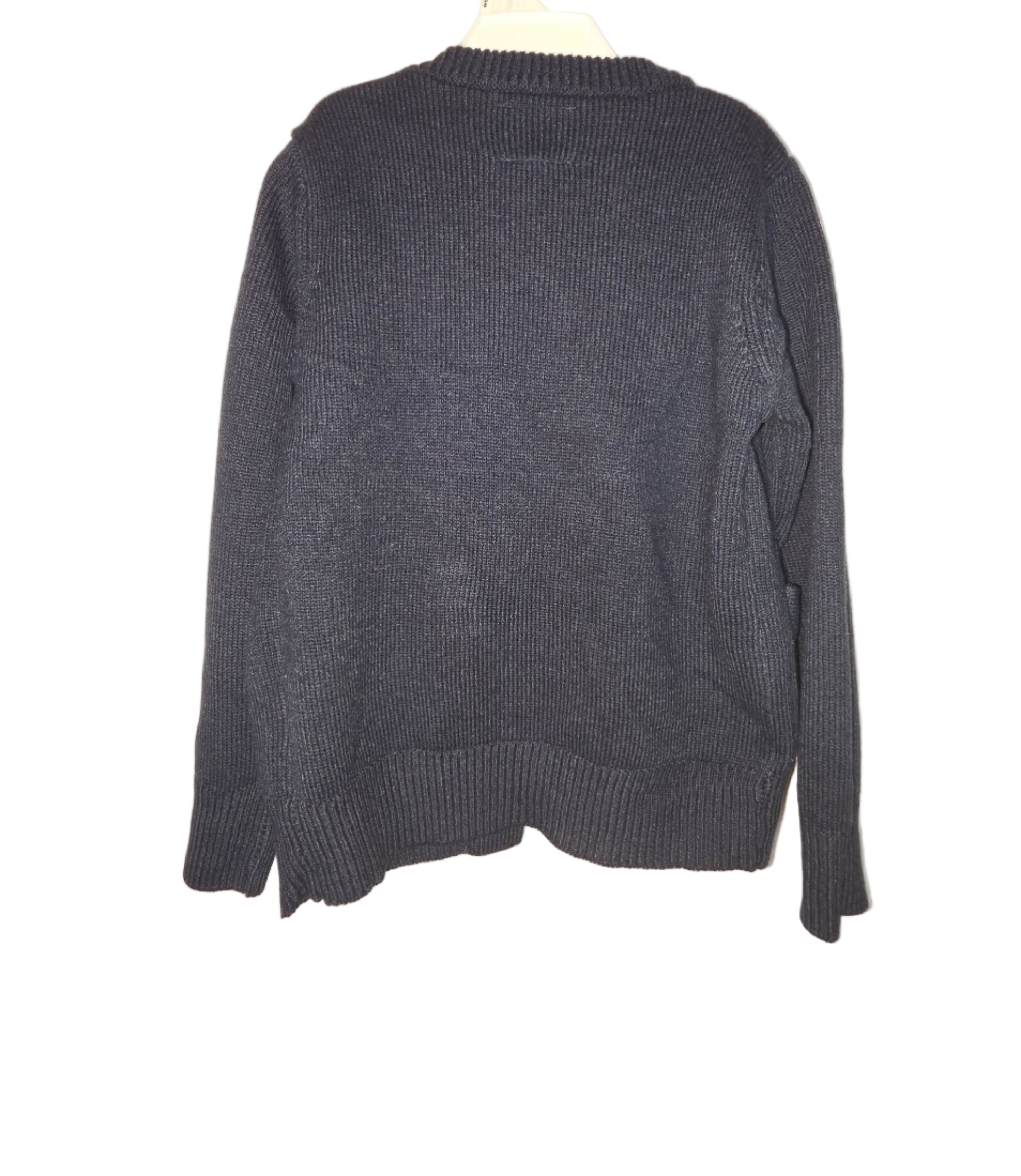 Folded dark gray sweater on a light beige background