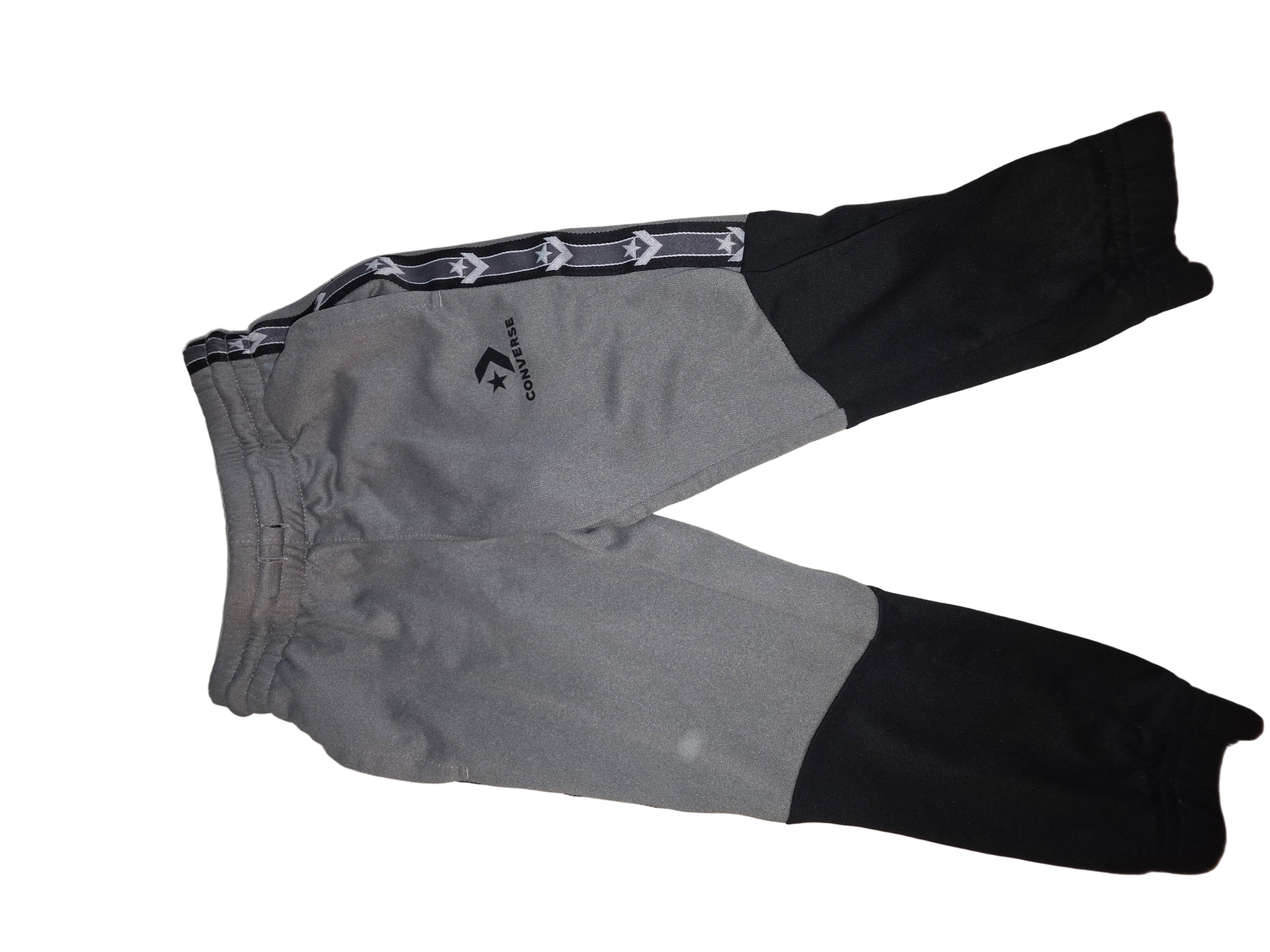 Gray and black pants with a brand logo on a beige surface