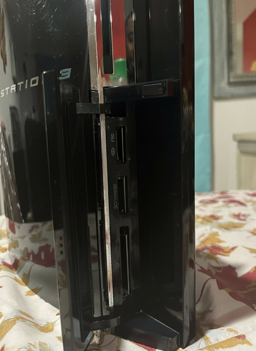 Black gaming console on a bed with a colorful blanket